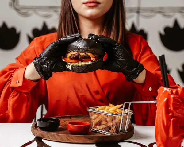 Жінка тримає в руках чізбургер з чорною булочкою — стокове фото