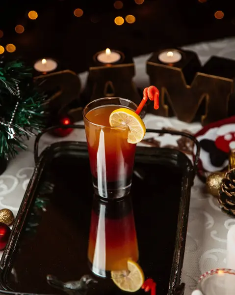 A glass of ombre cocktail garnished with lemon slice around christmas decorations — Stock Photo, Image