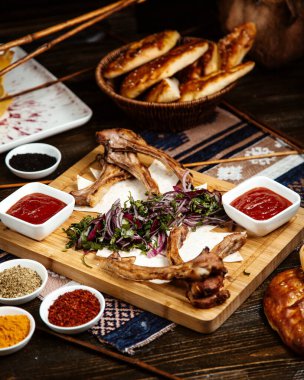 Kızarmış pirzola, yanında dilimlenmiş otlar ve soğan.