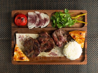 marinated beef steak served with rice smoked vegetables onion slices and bread