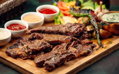 Soslu kuzu eti, ızgara biber, tahtada taze salata.