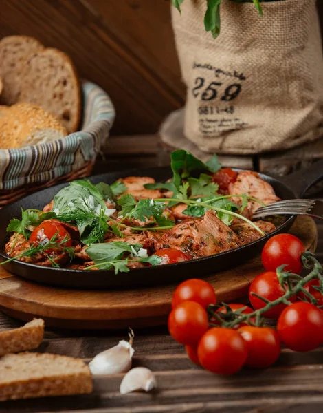 Ломтики маринованной баранины, украшенные помидорами и свежими травами в чугунной тарелке — стоковое фото