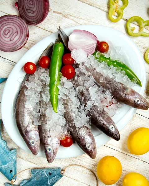 Plate of raw fish topped with pepper, cherry tomato and red onion — Stock Photo, Image