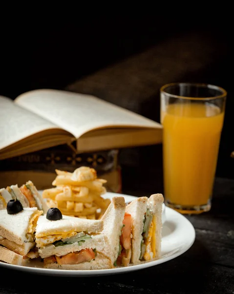 Sandwich club avec poulet oeuf concombre tomate et un verre de jus d'orange — Photo