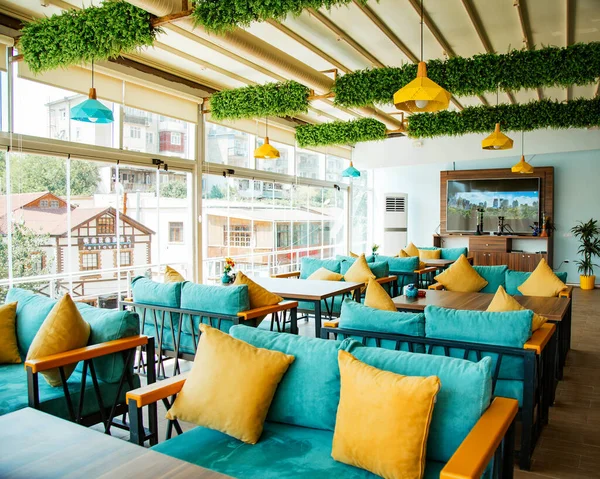 Cafe terrace with turquoise sofas and yellow pillows — Stock Photo, Image