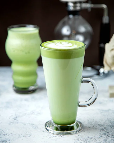 Un vaso de té verde matcha con arte latte en la parte superior — Foto de Stock