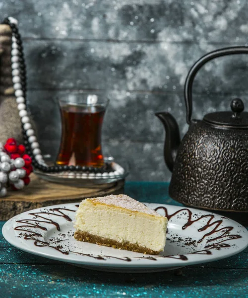 Rebanada de pastel de queso en plato blanco servido con té negro — Foto de Stock