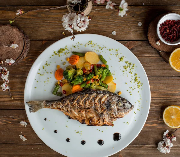 Gebratener Fisch mit Gemüse im Teller — Stockfoto