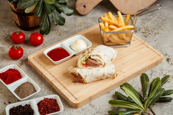 Enveloppement de viande dans du pain plat servi avec des frites et des sauces — Photo