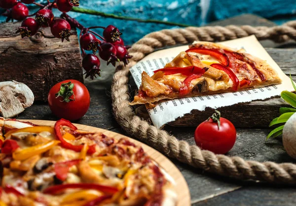 En bit pizza och tomater på bordet — Stockfoto