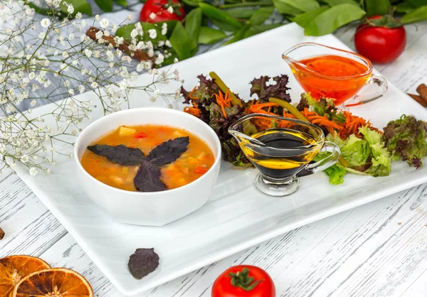 Miska zupy warzywnej serwowana z oliwą, świeżą sałatką i sosem chili — Zdjęcie stockowe