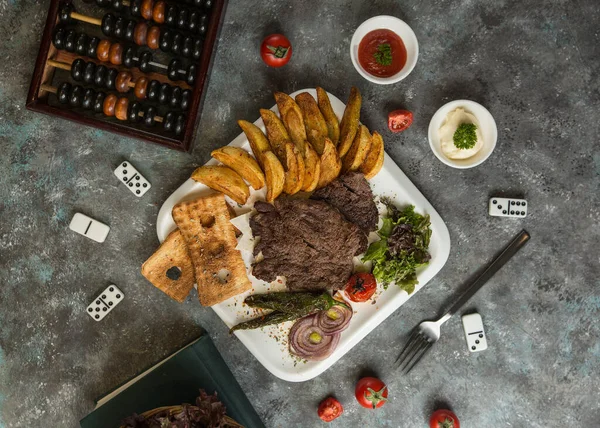 야채와 함께 양념 한 쇠고기 스테이크는 튀긴 감자, 크래커, 샐러드와 함께 내놓는다 — 스톡 사진