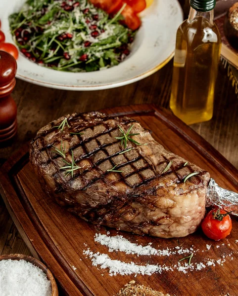 Grilled steak with salt herbs and grilled tomato served on wooden board — Stock Photo, Image