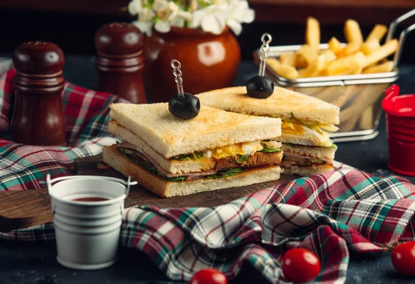 Club sandwich dengan telur, selada, salami, mentimun, tomat, disajikan dengan kentang goreng — Stok Foto