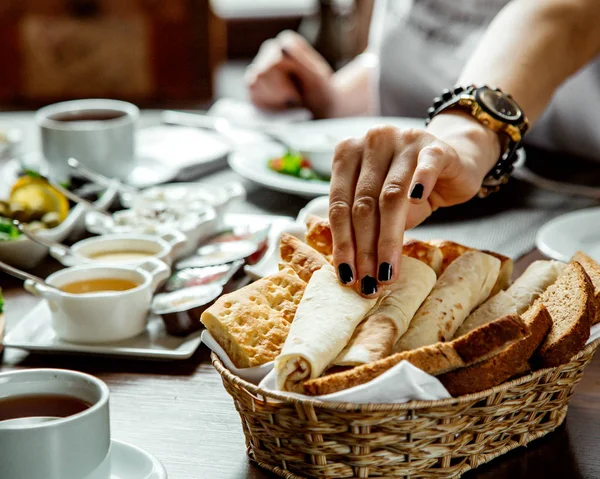 Woman taking lavash from bread basket — Stock Photo, Image