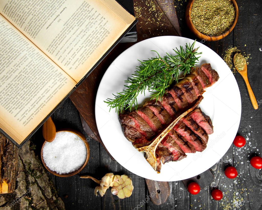 medium rare steak, dried herbs, tomatoes, salt and an open book