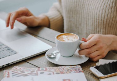 Masada dizüstü bilgisayarı olan sıcak cappucino.