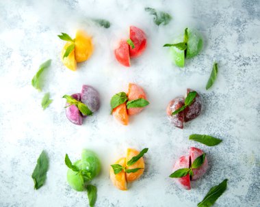 Nane yapraklarıyla süslenmiş yarı kesilmiş donmuş meyvelerin üst görüntüsü