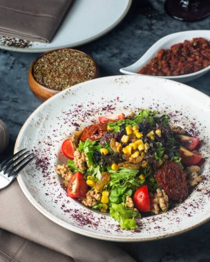 Bir tabak yeşil salata, marullu, cevizli, mısır ve kuru üzüm.