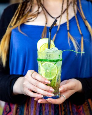 Kız elinde bir bardak buzlu ve limonlu soda tutuyor.