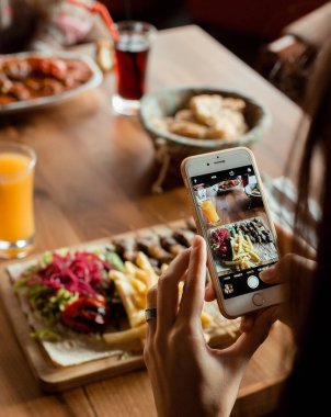 Tikka kebap ve salatayla öğle yemeği fotoğrafı çeken bir kadın.