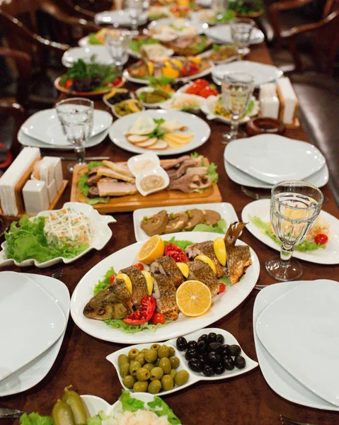 Esstisch mit Fisch, Salaten und Beilagen — Stockfoto