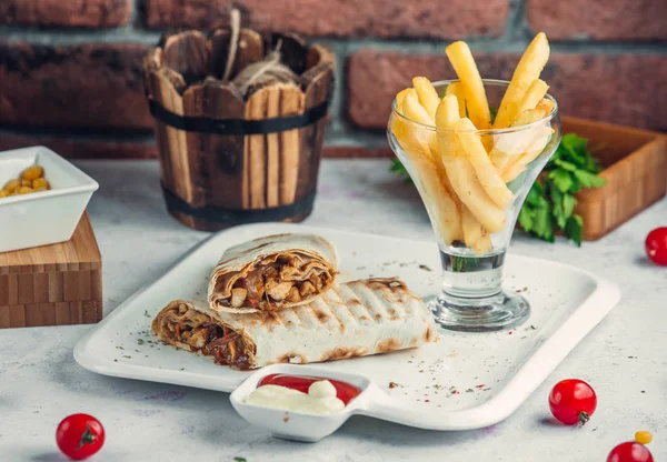 Lavaşlı tavuk çevirici ve tabağında patates kızartması.