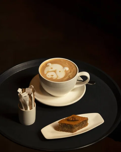 Tasse Cappuccino mit Dog Latte Art serviert mit Pakhlava im dunklen Hintergrund — Stockfoto