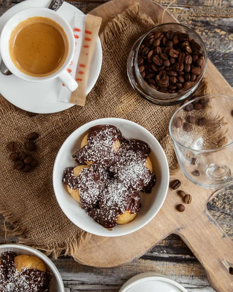 Vista superior de tigela profiterole coberto com molho de chocolate com polvilhas de coco — Fotografia de Stock