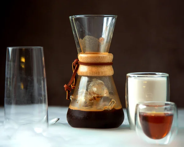 a glass of coffee in unique shaped glass served with milk and syrup