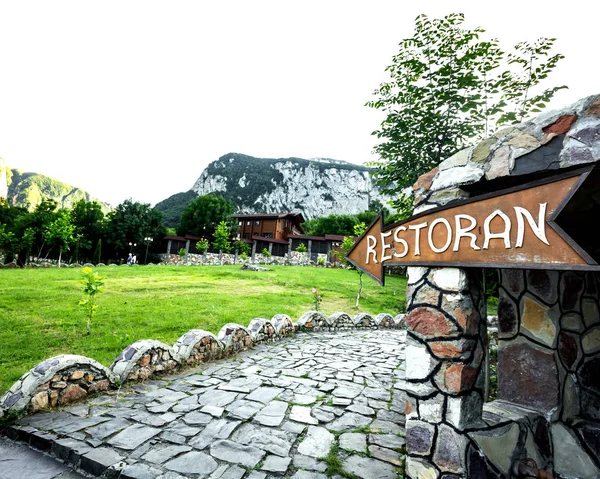 Restaurante ponteiro seta de madeira, grama verde e vista para a montanha — Fotografia de Stock