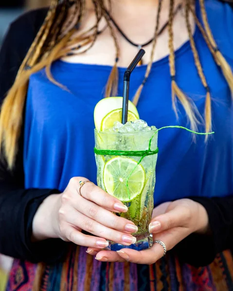 Girl holds a glass of sparkling water with ice and lime — Stock Photo, Image