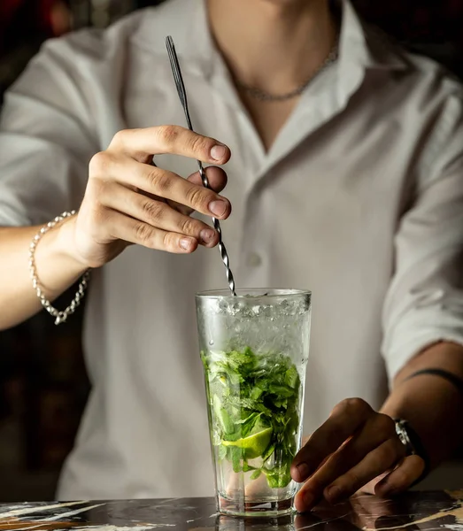 Barman míchá mojito koktejl s kovovou lžičkou — Stock fotografie