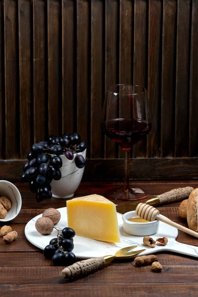 Queso parmesano sobre tabla de mármol servido con vino y uva —  Fotos de Stock