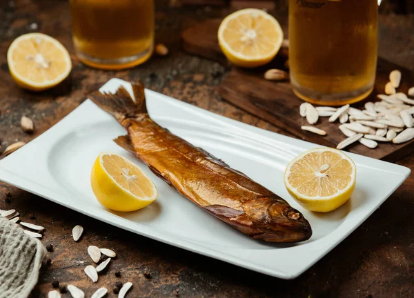 Dried smoked fish served with lemon halves, salty sunflower seeds and beer