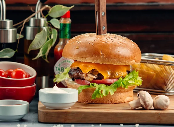 Burger wołowy z pieczarkami, świeżymi pomidorami, sałatą, serem i frytkami — Zdjęcie stockowe
