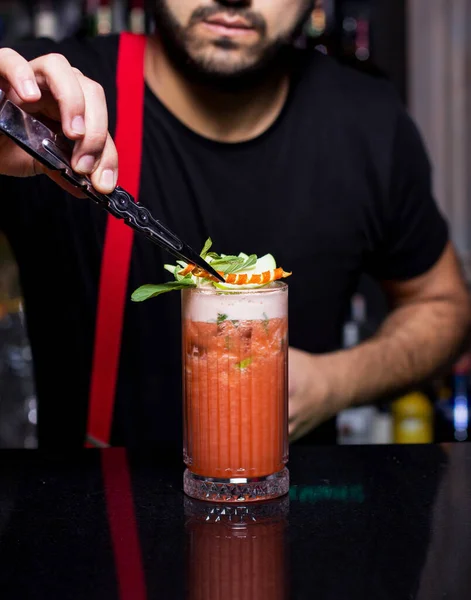 Barman zet sinaasappelschil op een glas sinaasappel- en appelcocktail — Stockfoto