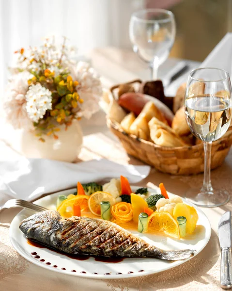 Sepiring ikan panggang disajikan dengan sayuran rebus dan irisan jeruk — Stok Foto
