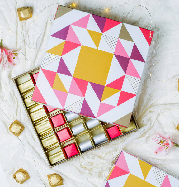 красочная коробка шоколада с золотыми, розовыми и белыми обложками
