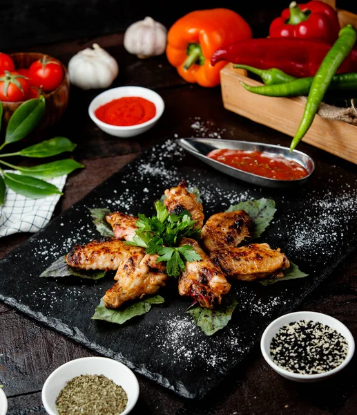 Ailes de poulet frit avec sauce dans des plats noirs — Photo