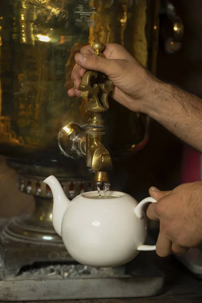 Homem que enche a panela de chá com água quente de samovar — Fotografia de Stock