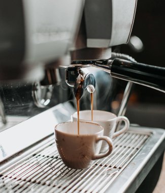 Kahve makinesinin altında iki espresso bardağı var.