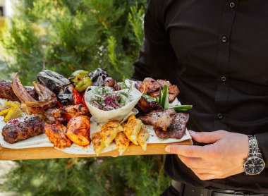 Elinde ızgara kebap tabağı tutan adam.