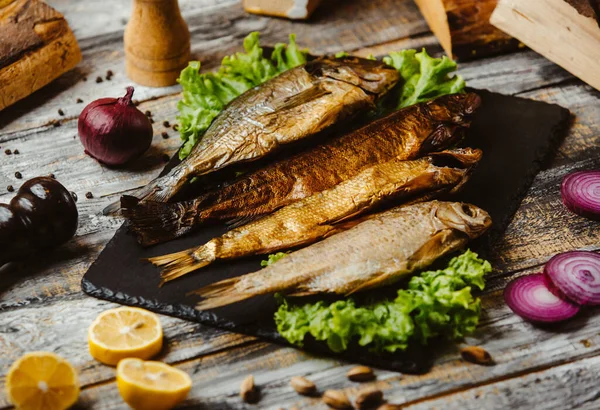 Smoked fish served on black serving board — Stock Photo, Image