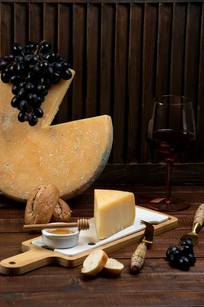 Кусок сыра пармезан подается с медом и виноградом — стоковое фото