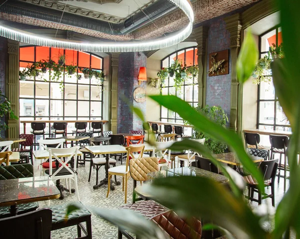 Geniş pencereli, ahşap ve deri sandalyeli kafe.