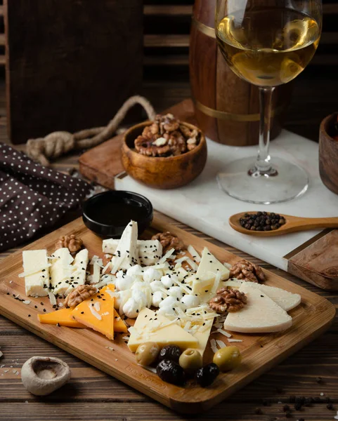 Plato de queso sobre tabla de madera con vino blanco — Foto de Stock