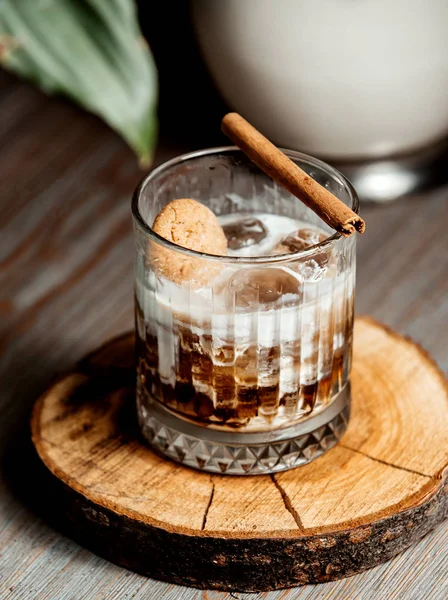 a glass of iced coffee cocktail garnished with cinnamon stick