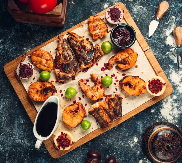 Gegrilde vis in stukken gesneden geserveerd op plat brood met sauzen, sumak — Stockfoto