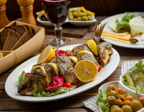 Roasted fish served with lemons and pomegranate with cheese plate